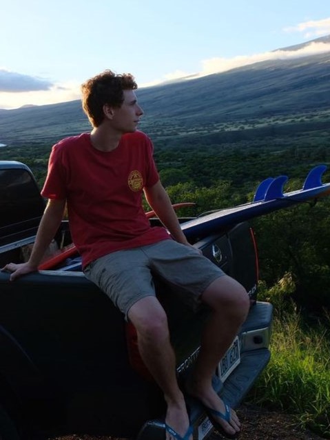 Keilan sitting at the back of a pickup truck, overlooking the scenery.