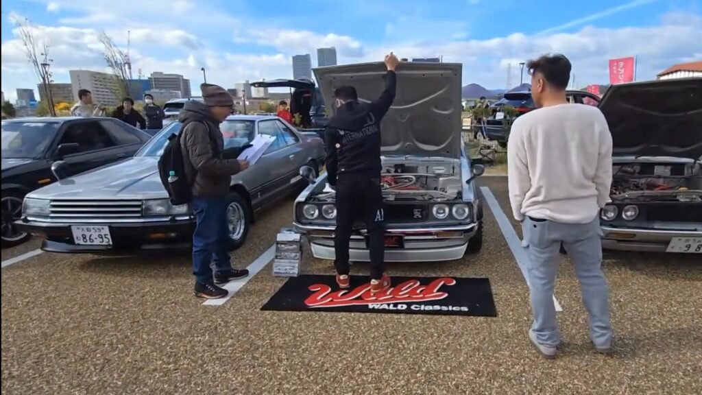 Event judges inspecting a classic car owner's vehicle for scoring